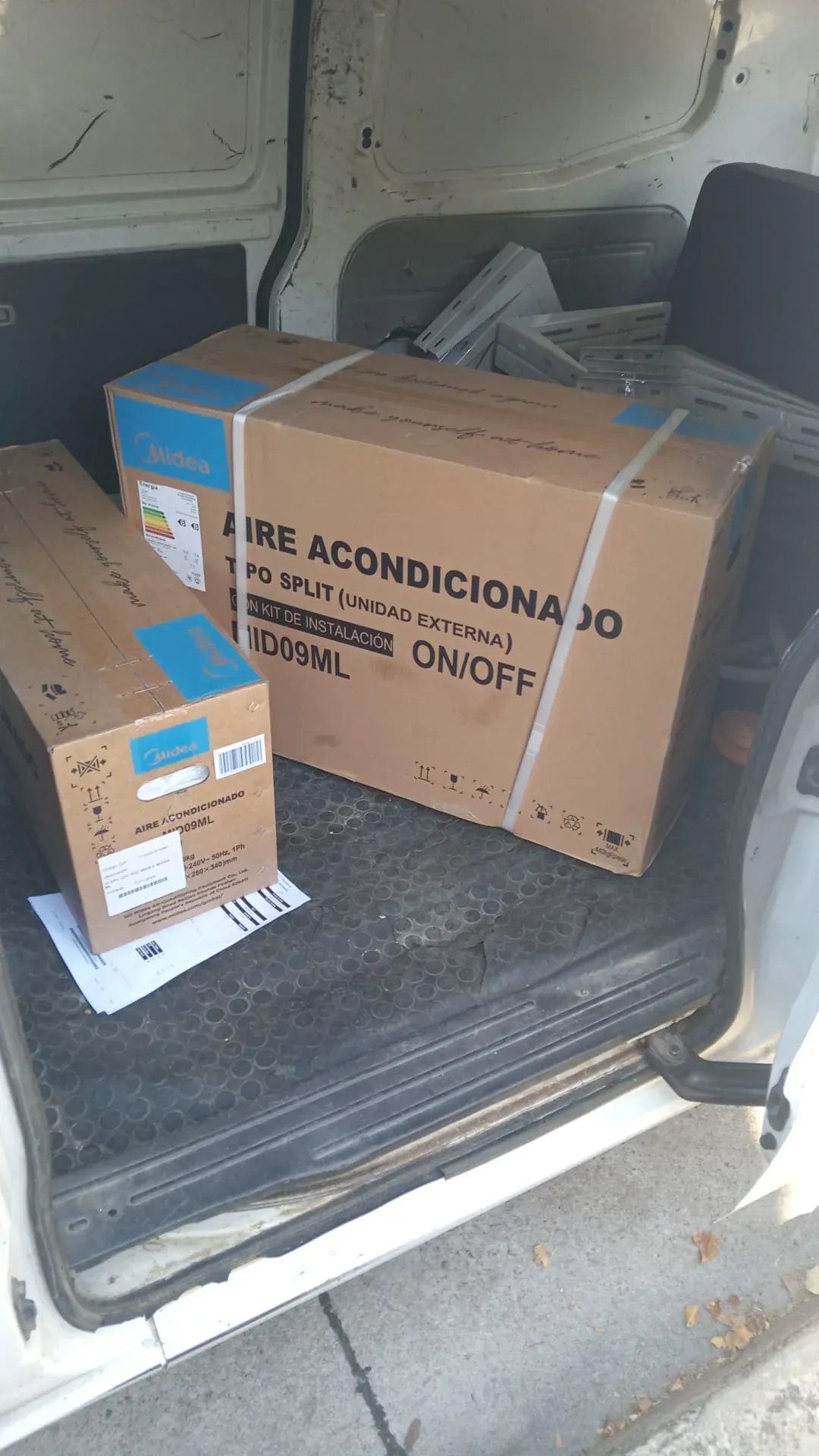 Dos cajas de aire acondicionado split Midea con kit de instalación y soportes en la camioneta, listas para instalar